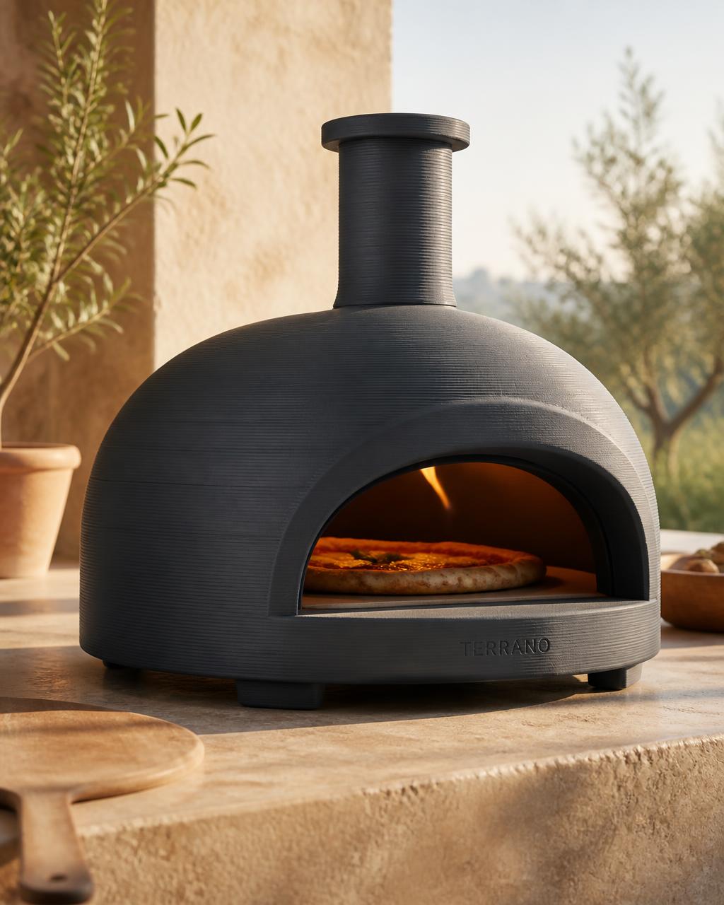 A modern matte charcoal ceramic 3D-printed pizza oven on a warm stone surface